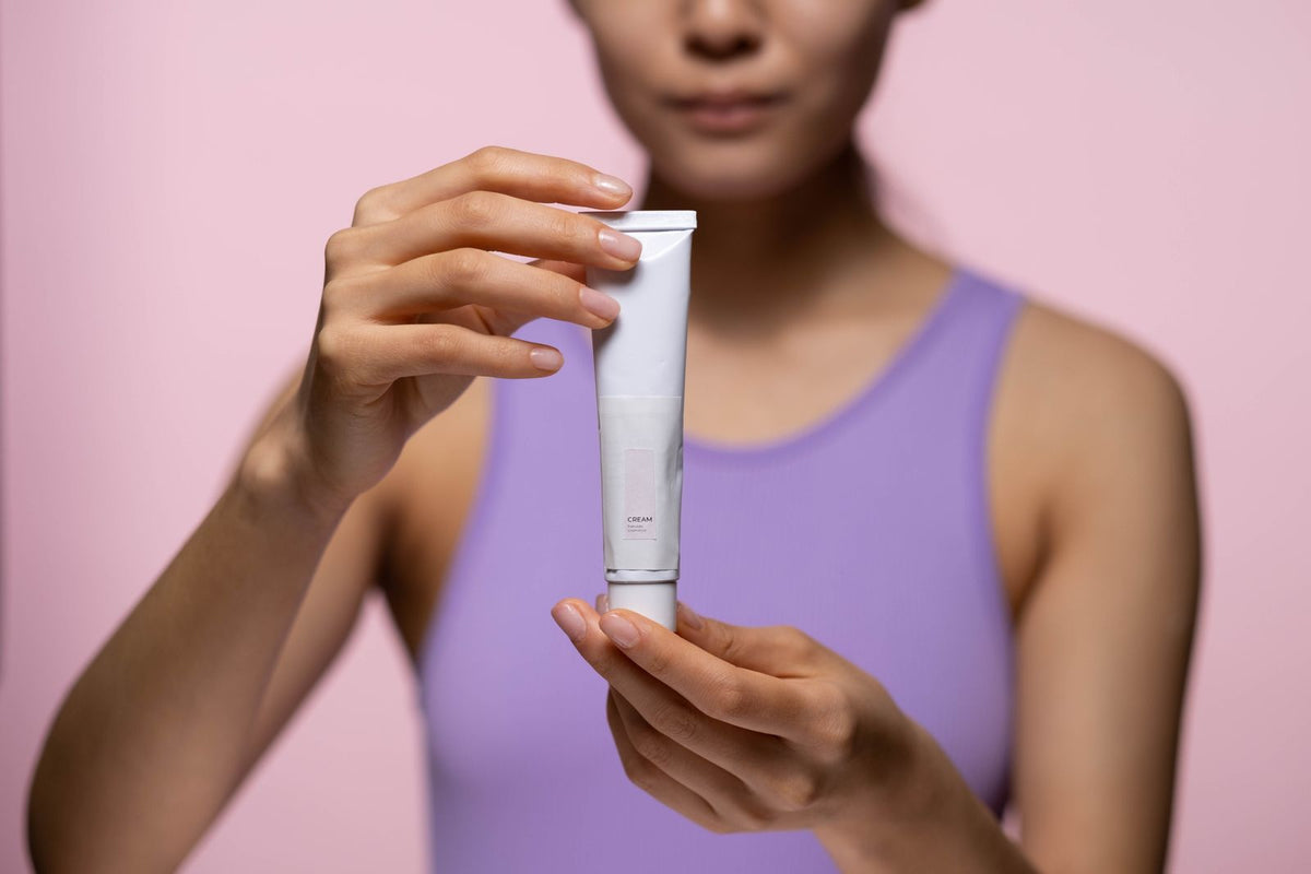 Hero alt - woman holding skincare cream studio